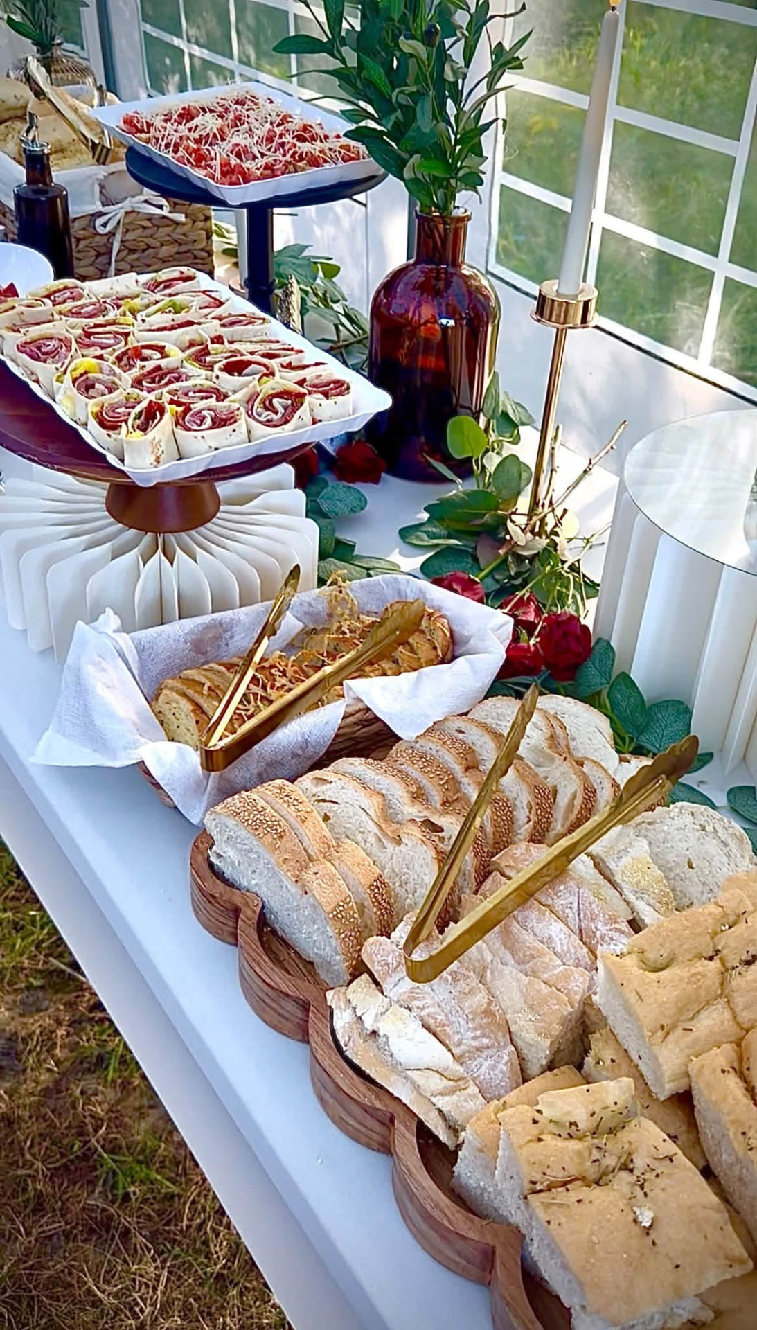 A catering display of sliced Italian breads, pinwheel wraps and tomato bruschetta